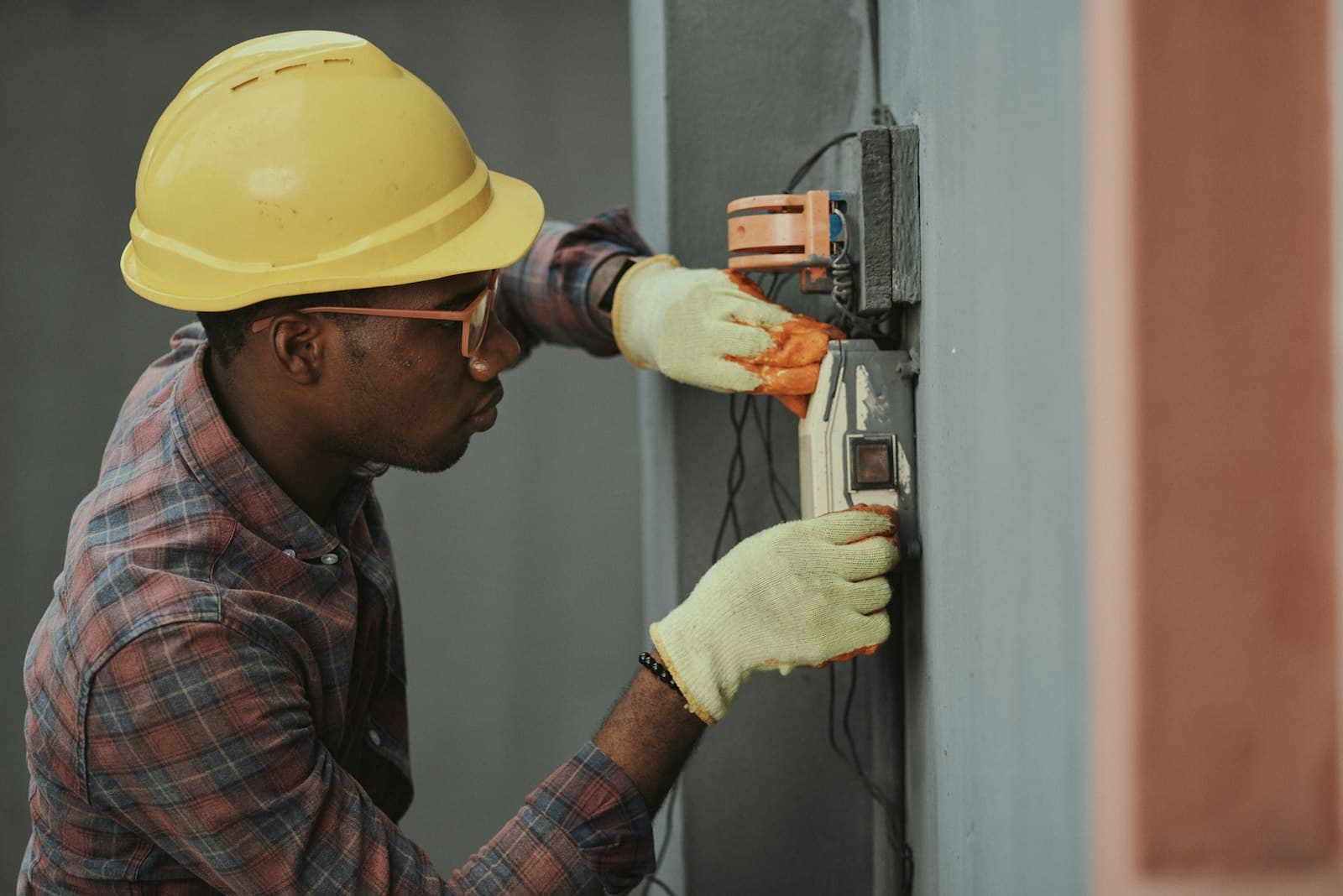 An engineer working on electrical equipment fixed to an outside wall